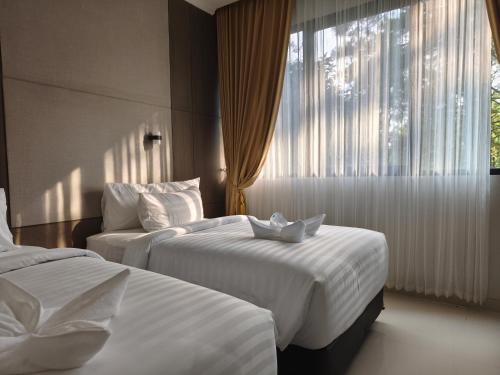 ein Hotelzimmer mit zwei Betten und einem Fenster in der Unterkunft BBIB Suites in Wonorejo