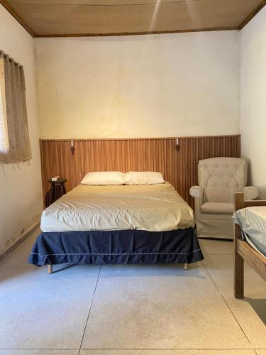 a bedroom with a bed and a chair at Recanto da Caluninha in Esmeraldas