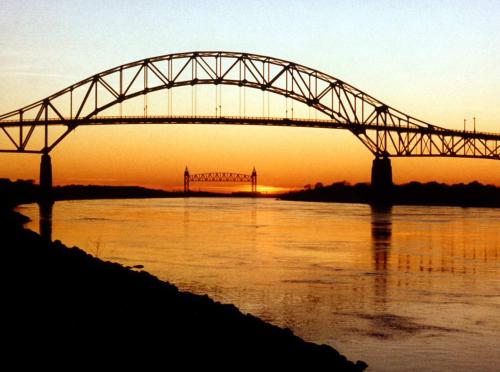 a bridge over the water with the sun setting at Buzzards Bay Family Beach Firepit CapeCodCanal in Bourne