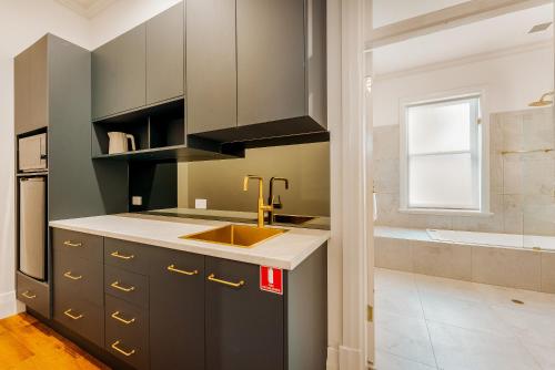 a kitchen with gray cabinets and a sink at Kincraig Hotel in Naracoorte