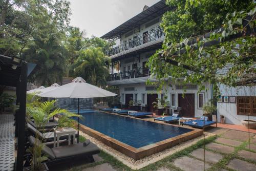 a swimming pool in front of a building with an umbrella at The Local Time Village in Siem Reap