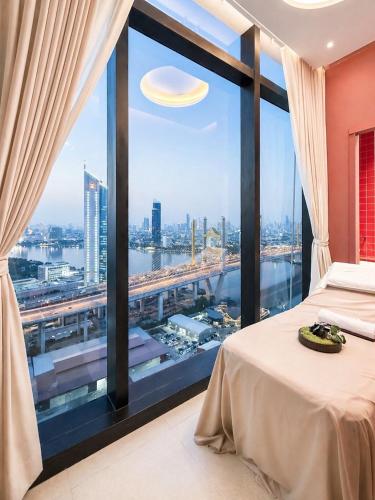 a bedroom with a large window with a view of a city at Luxury Riverside Condo with riverside pool in Bangkok
