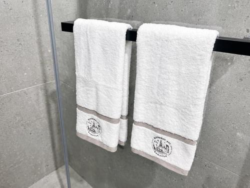 three white towels are hanging on a rack in a shower at Luxury Riverside Condo with riverside pool in Bangkok