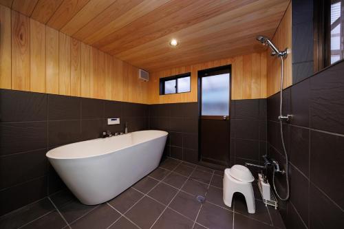 a bathroom with a white tub and a toilet at Hagizen in Hagi
