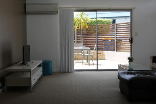 a living room with a television and a sliding glass door at Azure in Bridport