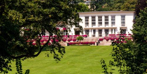a large white building with pink flowers in a yard at Dolce by Wyndham Bad Nauheim in Bad Nauheim