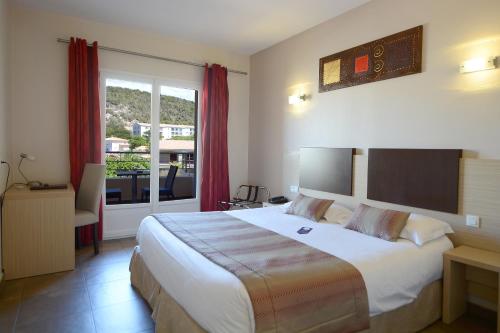 a hotel room with a large bed and a balcony at Hôtel A Madonetta in Bonifacio