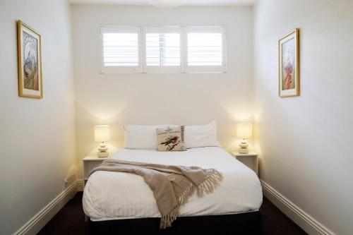 a bedroom with a bed with two lamps and a window at Historic Getaway in Launceston