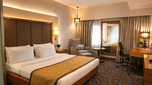 a hotel room with a bed and a desk at Pride Plaza Hotel, Ahmedabad in Ahmedabad