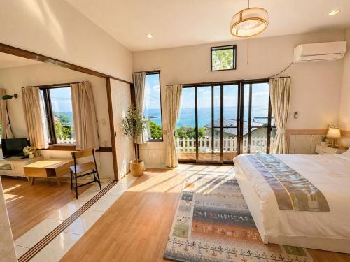a bedroom with a large bed and large windows at Villa Amoria in Miyazaki