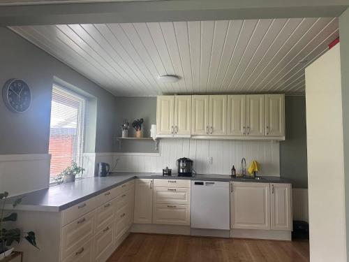 a kitchen with white cabinets and a white dishwasher at Family private house in Brovst
