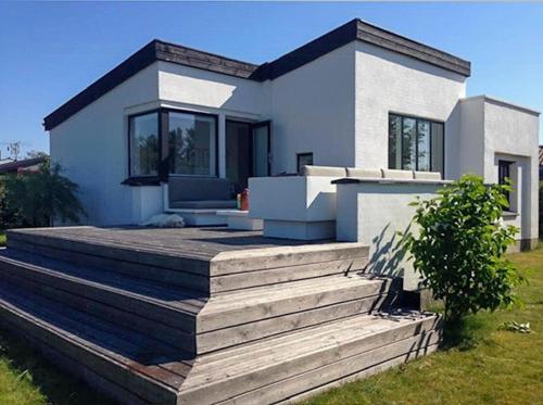 a small white house with a wooden deck at Functionalist House Only 100 Steps To The Beach in Haderslev