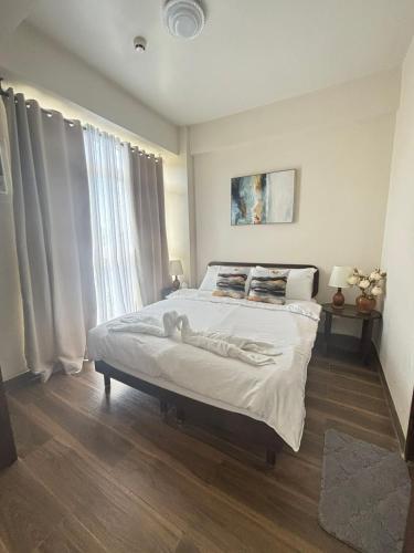 a bedroom with a bed with white sheets and a window at Ocean Garden Villas Cluster B 3rd Floor Unit C in Boracay