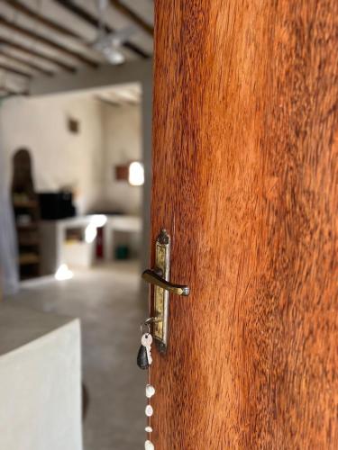 a wooden door with a key in a room at Bahari Studio by Bora Pamoja Homes Pool, Solar Backup & 5 Min to Beach in Jambiani