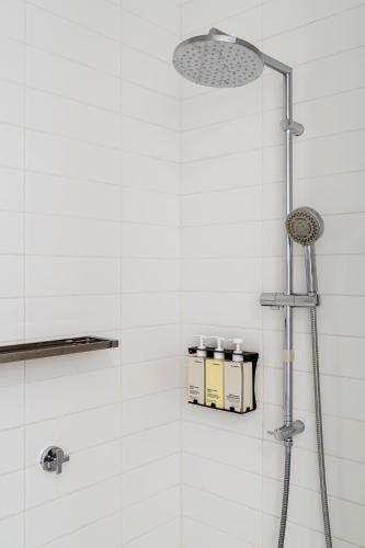 a shower in a bathroom with white tiles at Tyrian Albert Park Lake in Melbourne