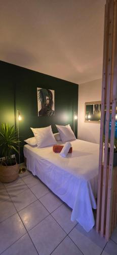a bedroom with a large white bed with a green wall at Fare Iki in Papeete