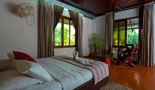 a bedroom with a large bed in a room with windows at Sampan Cafe and Resort in Cox's Bazar
