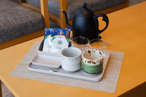 a tray with cups and a tea set on a table at KIORI Hotel Takakura in Kyoto