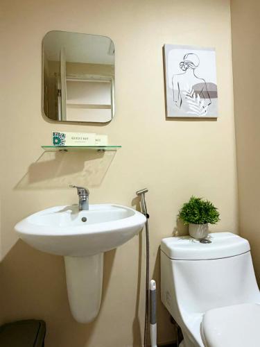 a bathroom with a sink and a toilet and a mirror at AnR Condo at Avida Towers in Cagayan de Oro