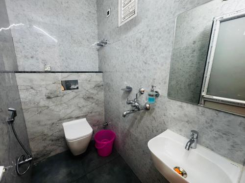 a bathroom with a sink and a toilet and a mirror at Regal Palace Hotel and Banquets in Patna