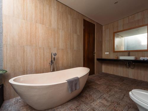 a bathroom with a bath tub and a sink at Prawara Uluwatu in Uluwatu
