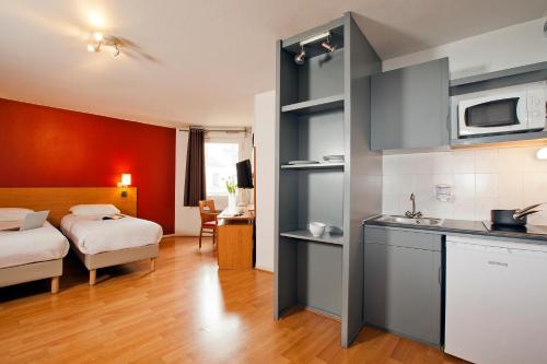 een slaapkamer met een bed en een keuken met een wastafel bij Séjours & Affaires Lyon Saxe-Gambetta in Lyon