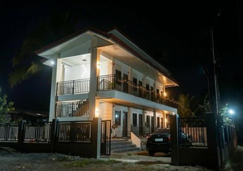 a white house with a balcony at night at Negradas Transient Inn-with Air-conditioning in Manolo Fortich