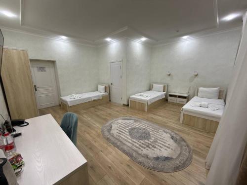 a room with two beds and a large rug at STATUS HOTEL in Qarshi