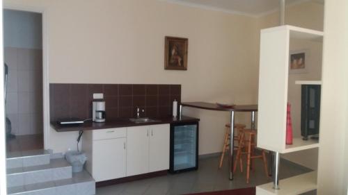 uma cozinha com armários brancos e uma mesa e cadeiras em Barokk Antik Guest Hause em Kecskemét