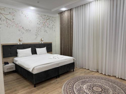 a bedroom with a large bed and a rug at STATUS HOTEL in Qarshi