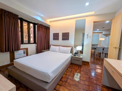 a bedroom with a large white bed and a kitchen at Prince Plaza II Condotel in Manila