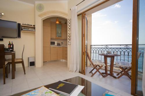 een woonkamer met een tafel en een balkon bij Ascot By The Sea in St Paul's Bay