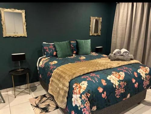 a bedroom with a large bed with a floral blanket at Dragonfly in Boksburg