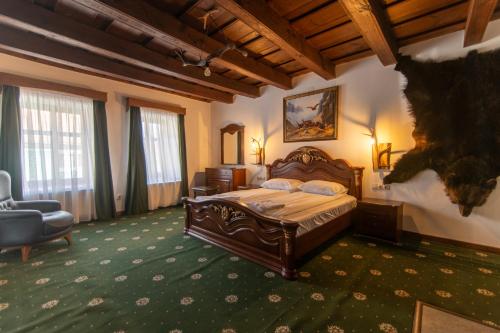a bedroom with a bed and a chair in a room at Rácz Vadászkúria in Racoşu de Sus