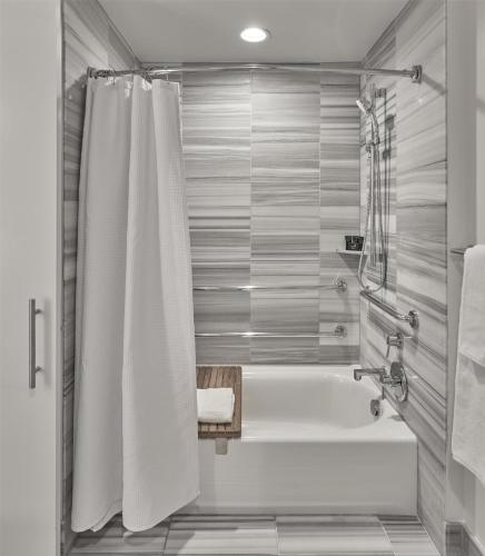 a white bathroom with a tub and a shower at Hyatt Centric the Pike Long Beach in Long Beach