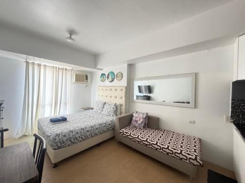 a bedroom with a bed and a couch and a mirror at Centrio Tower Condo Units in Cagayan de Oro