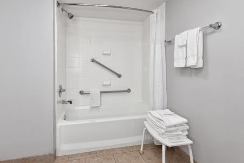 a white bathroom with a tub and a chair at La Quinta by Wyndham Dallas I-35 Walnut Hill Ln in Oldham