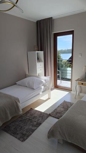 a white bedroom with a bed and a large window at Dom nad jeziorem Natalia SEA & LAKE in Kołczewo