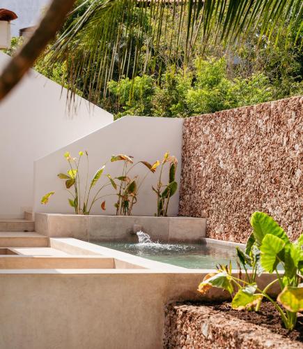 a pool of water in a garden with plants at Little Maua - Stylish Private Hideaway on Galu Beach in Galu