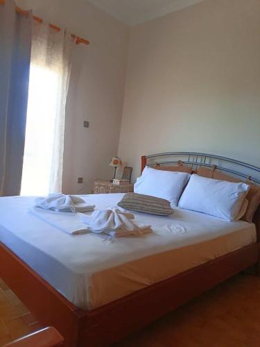 a bedroom with a bed with white sheets and a window at Cozy country house in Preveza