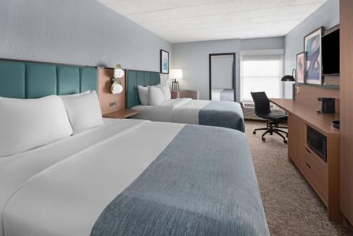 a hotel room with two beds and a desk at Wingate by Wyndham Cranberry in Cranberry Township