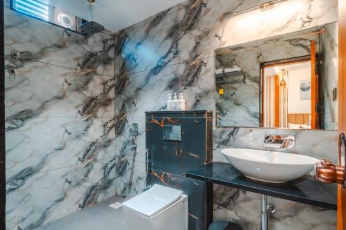 a bathroom with a sink and a marble wall at Travinities Hotel Shree Ji Palace in Ujjain