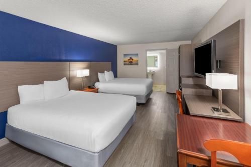 a hotel room with two beds and a television at Angel Inn Near IMAX, a Travelodge by Wyndham in Branson