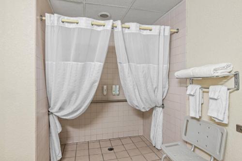 a bathroom with a shower with white curtains at Quality Inn & Suites in Grayling
