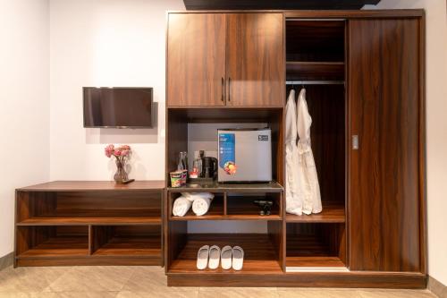 a large wooden cabinet with a television and shoes at LT Angkor Hotel in Phumĭ Réach Born (2)