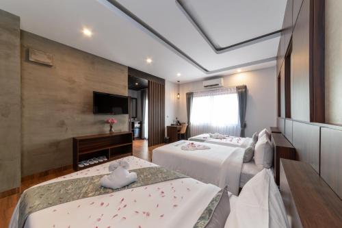a hotel room with two beds and a television at LT Angkor Hotel in Phumĭ Réach Born (2)