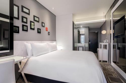 a bedroom with a large white bed and a desk at Protea Hotel Fire & Ice! by Marriott Pretoria Menlyn in Pretoria