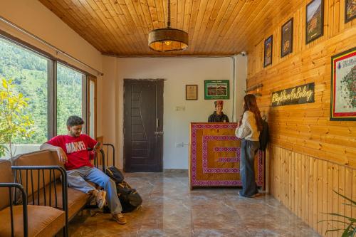 a man sitting in a chair in a room with a woman at The Social Stays Tirthan in Bandal
