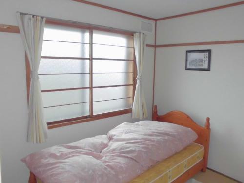 a bedroom with a bed and a window at プチキャンプ場おちぼの郷 in Furano