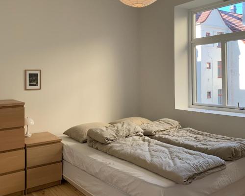 a bed in a white room with a window at Cozy Scandinavian design apartment in Bergen